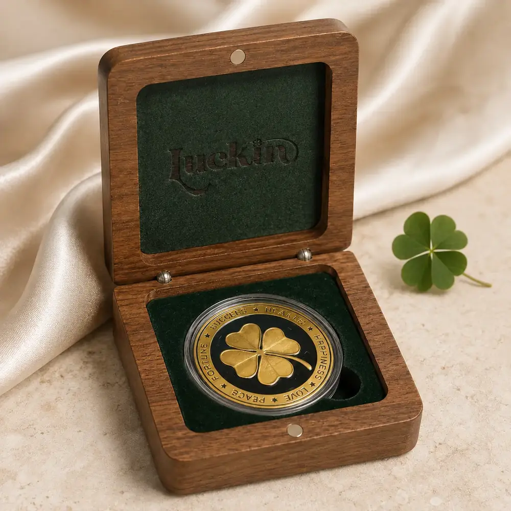 A gold Luckin Clover fortune coin stamped with a four-leaf clover, set into a wooden keepsake box.